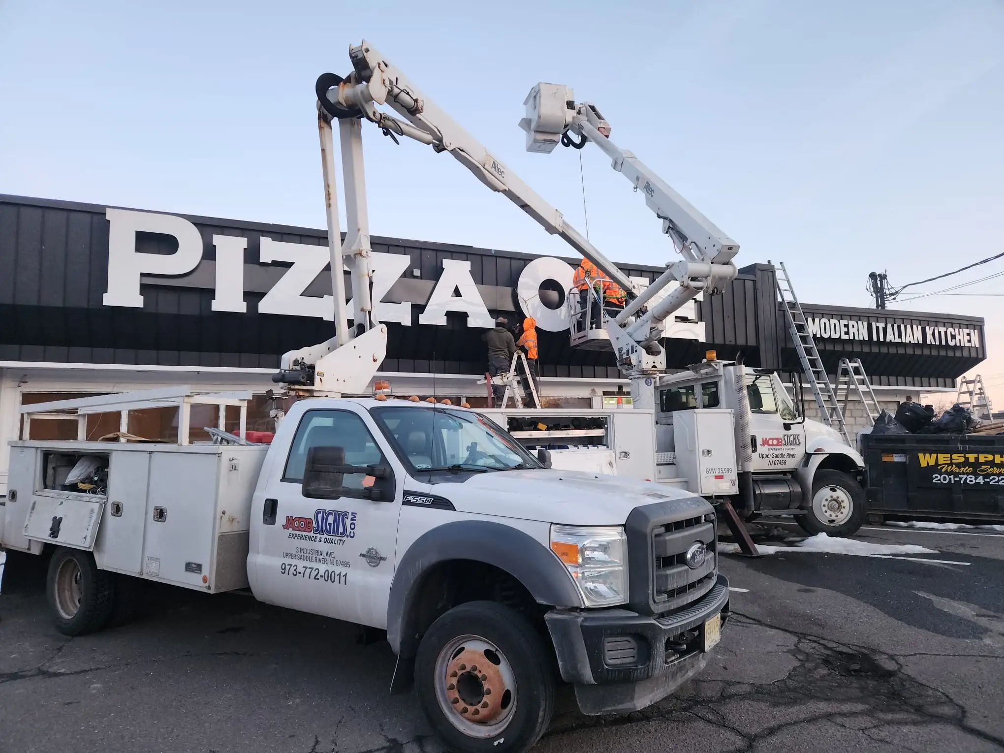 Bucket trucks installing exterior letters on a commercial property.