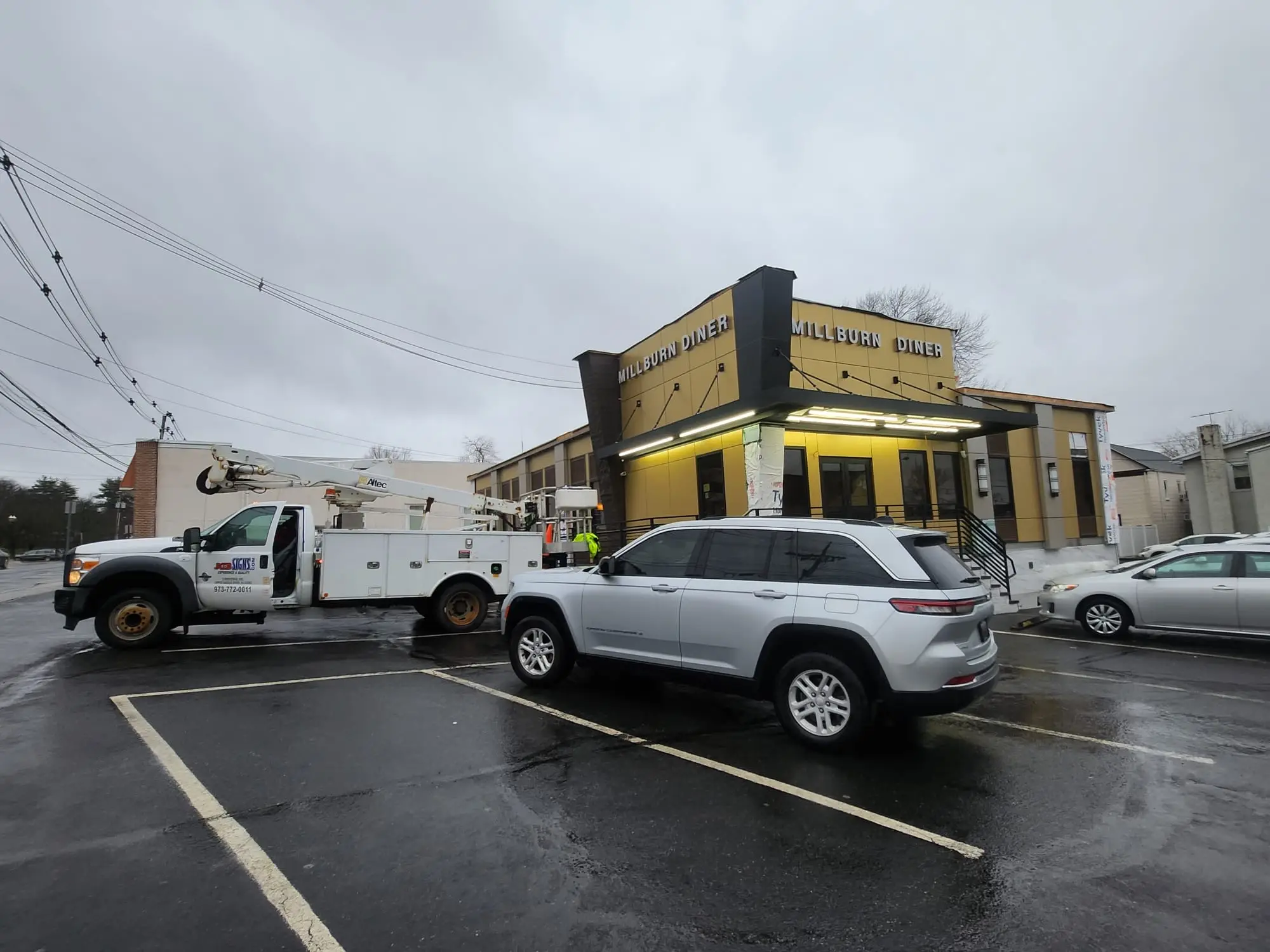 Service truck at a diner during commercial sign installation work.