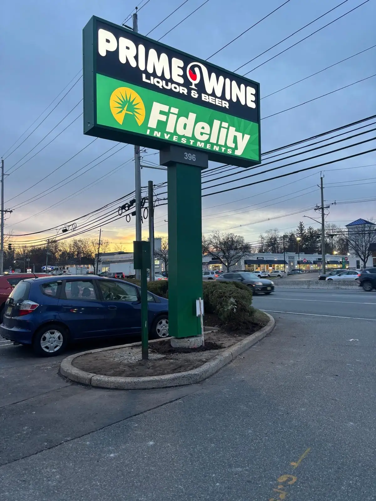Illuminated Prime Wine and Fidelity pylon sign beside a commercial roadway.